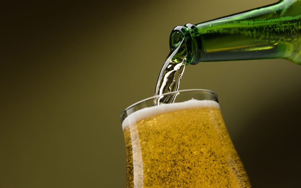Pouring fresh beer from a bottle into a glass, alcoholic drinks and celebration concept